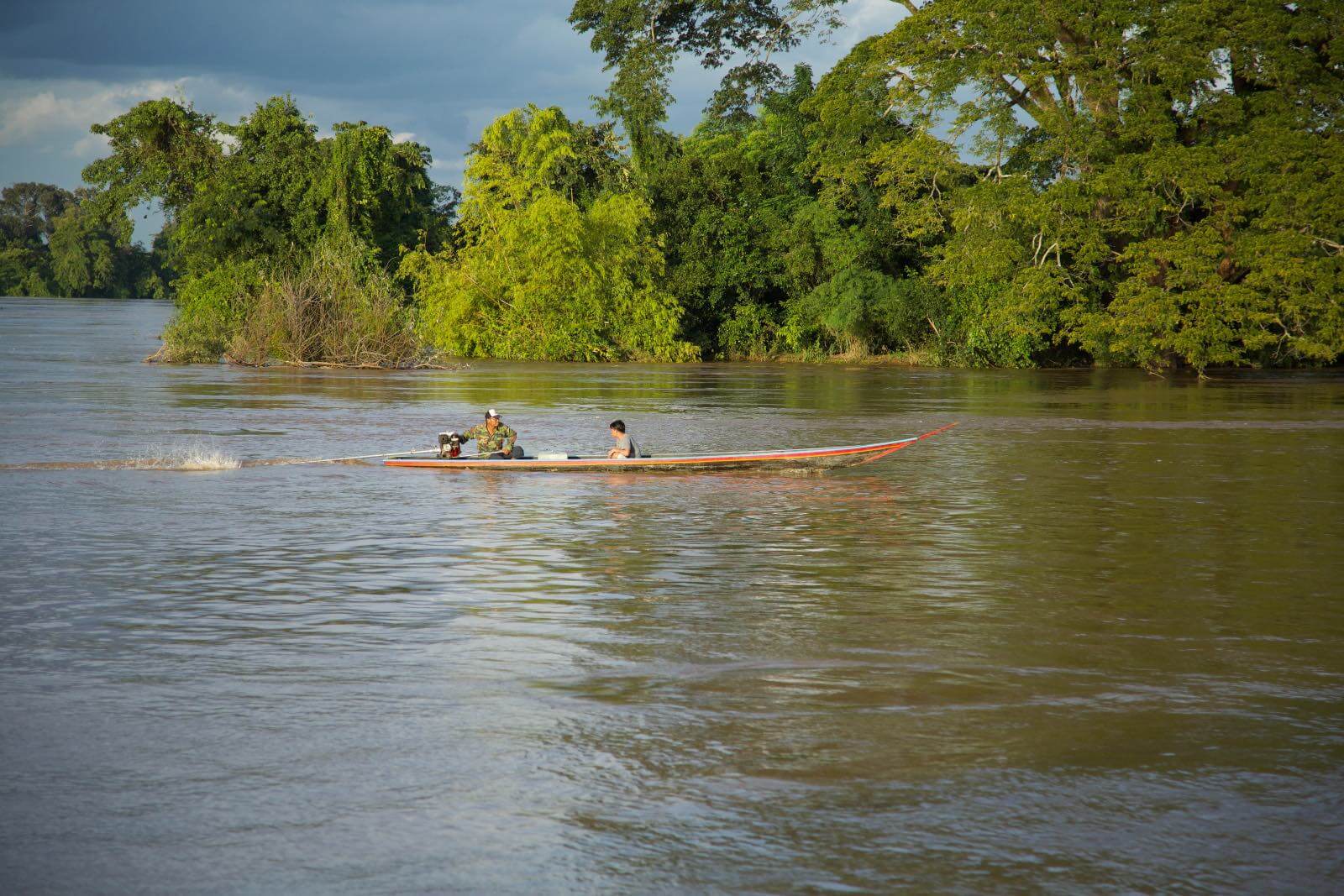Men driving a small boat on the Mekong River in Don Det, Laos-2 Men driving a small boat on the Mekong River in Don Det, Laos-2