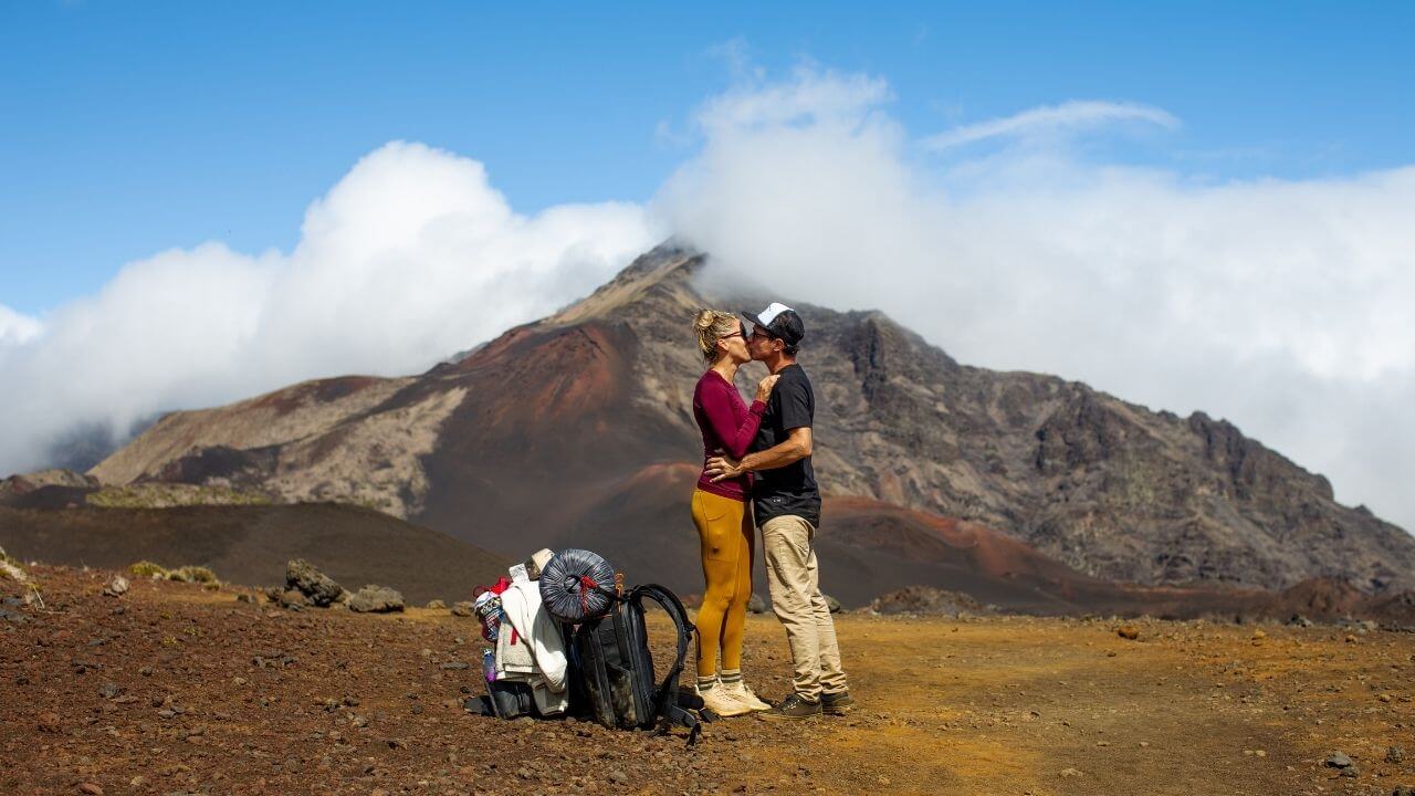 Travel couple kissing on a trail inside a dormant volcano 
