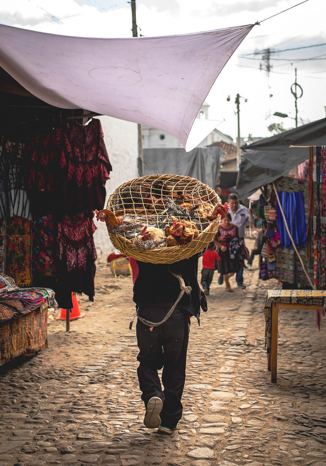 A man carrying a basket of chickens in the Chichi Market